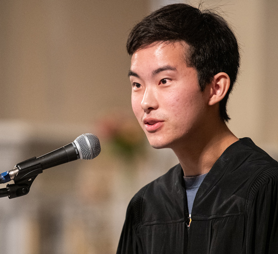 A woman in sunglasses claps in a crowd at a basketball game